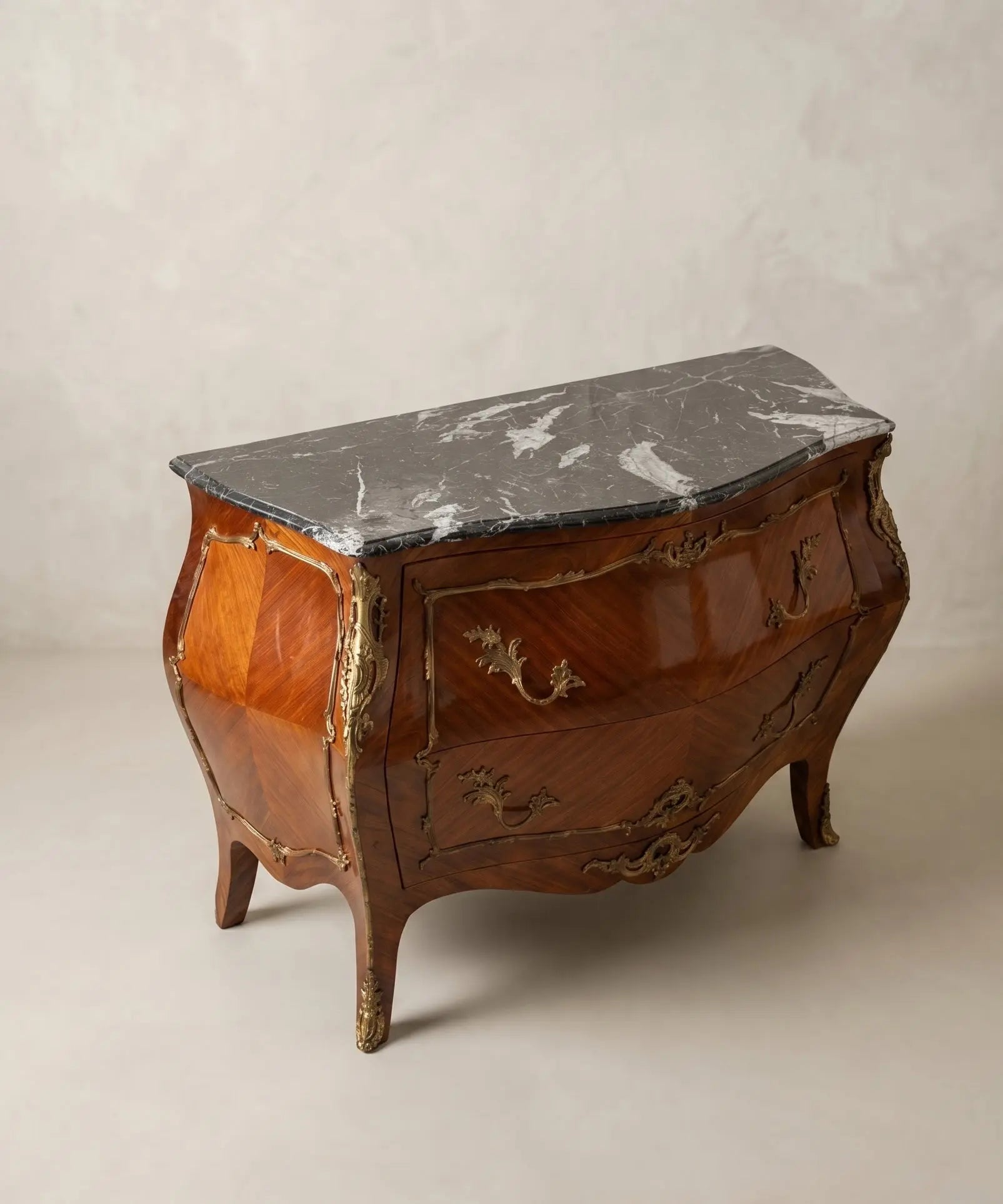 Primer plano de la marquetería en rombo y los herrajes de rocalla en bronce de una cómoda antigua francesa.