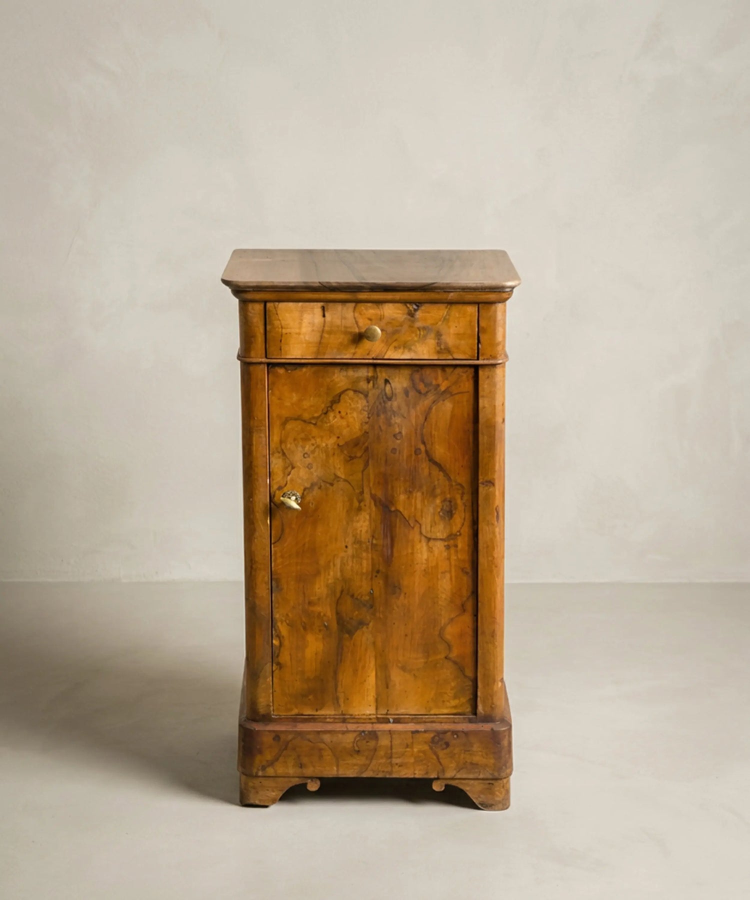 Mesita de noche antigua estilo Luis Felipe en chapa de raíz de nogal con cajón y puerta.