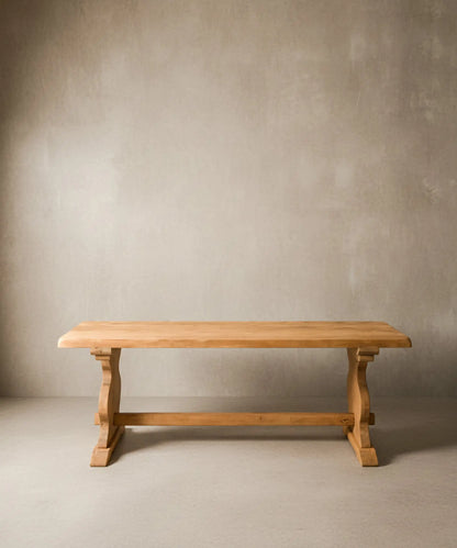 Mesa de comedor rústica de madera maciza vista de frente sobre fondo neutro, destacando el tablero grueso y el travesaño central.