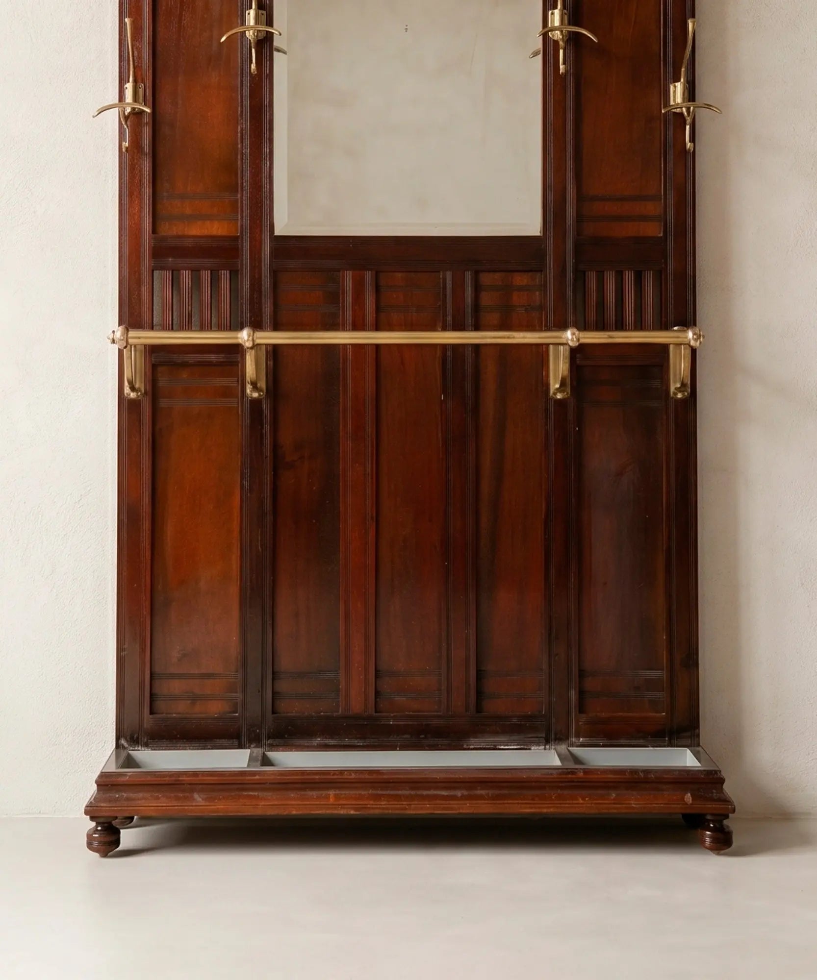 Barra paragüero de latón y bandeja recogegotas de zinc en recibidor de pared vintage.