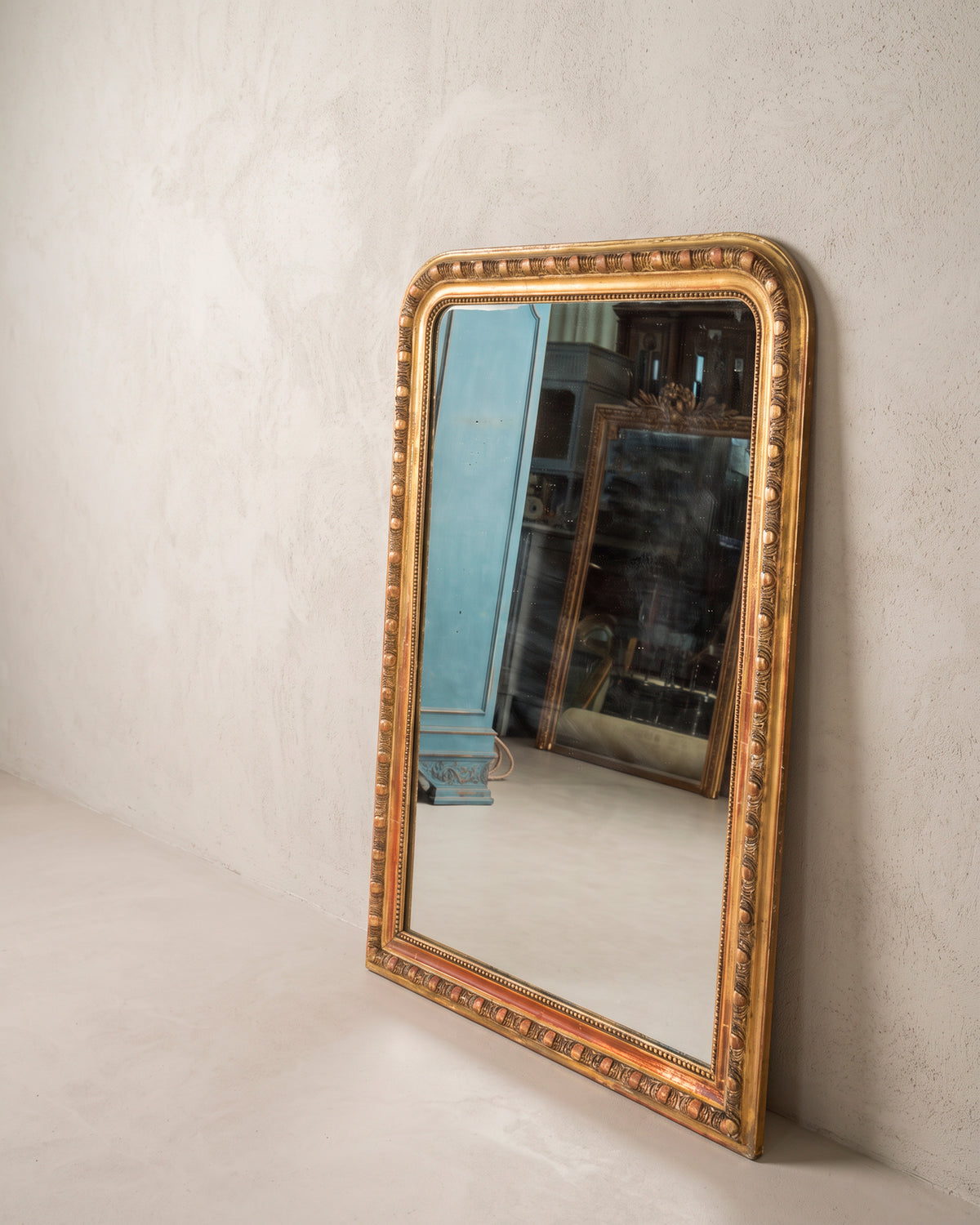 Espejo antiguo dorado vista lateral apoyado en la pared, friso de óvalos — Antique Arte y Decoración