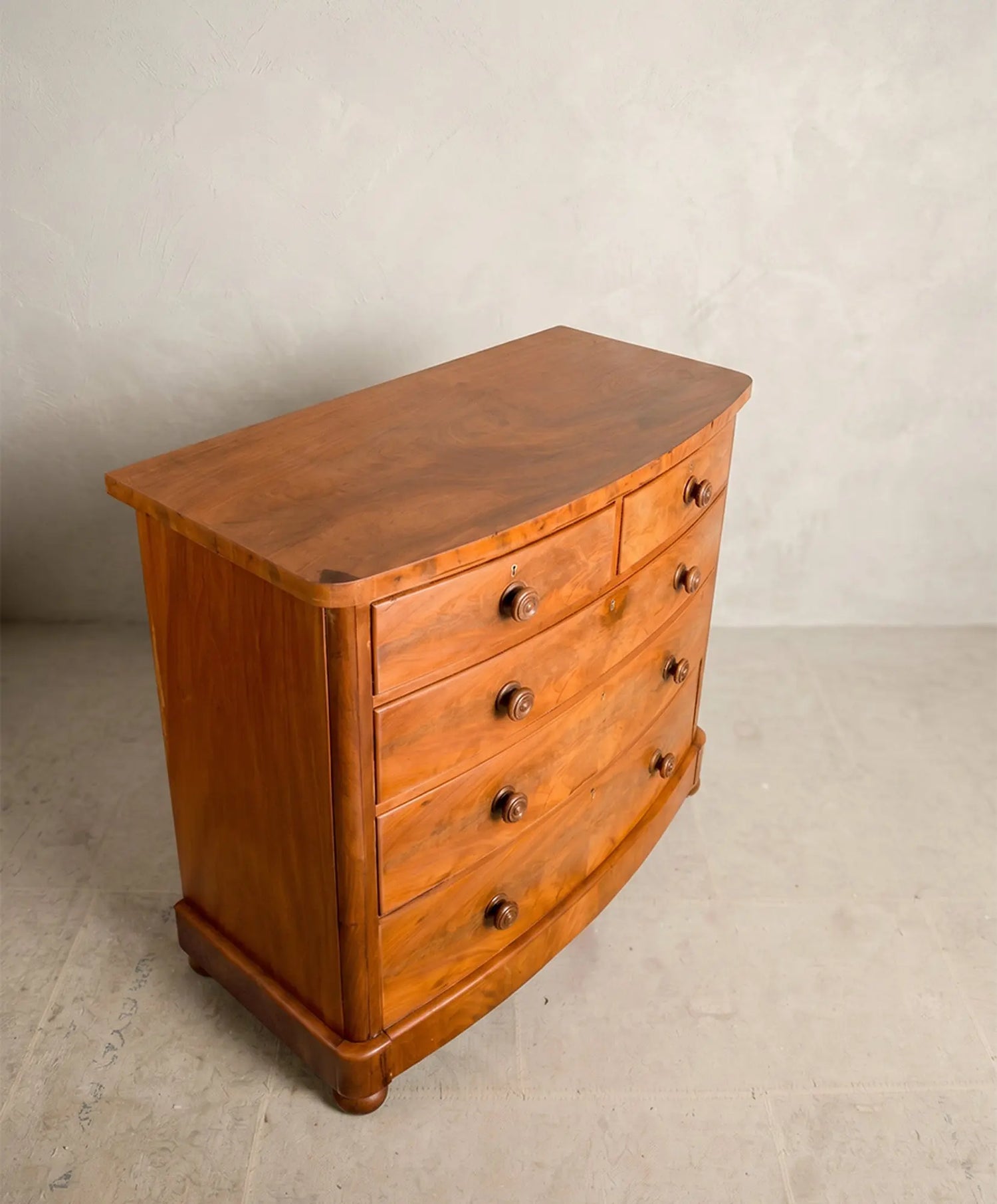Superficie curva de madera de caoba pulida de una cómoda antigua inglesa.