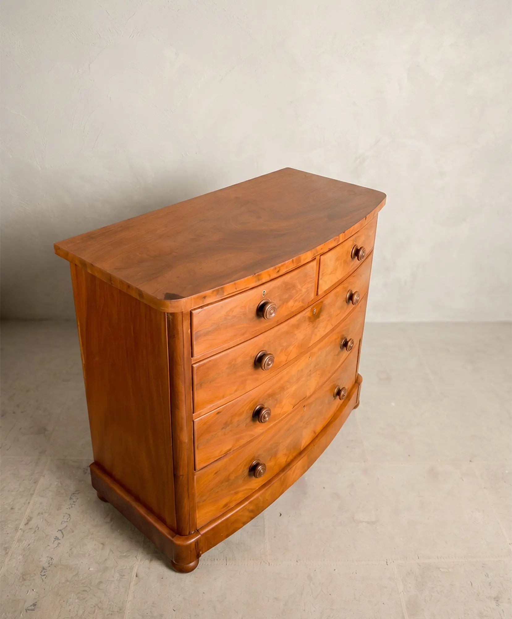 Superficie curva de madera de caoba pulida de una cómoda antigua inglesa.