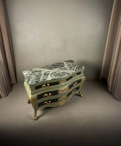 Vista lateral de la silueta curva "bombe" y los apliques de bronce en las esquinas.
