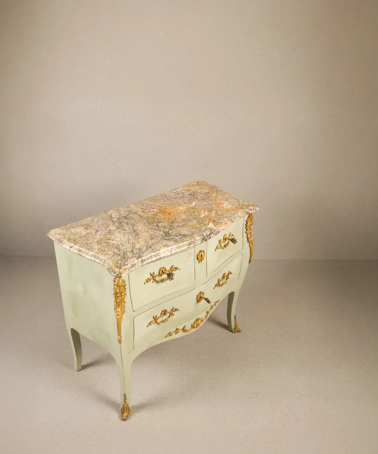 Vista superior de plancha de mármol antiguo veteado sobre cómoda francesa verde.