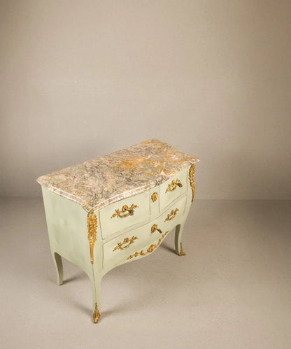 Vista superior de plancha de mármol antiguo veteado sobre cómoda francesa verde.