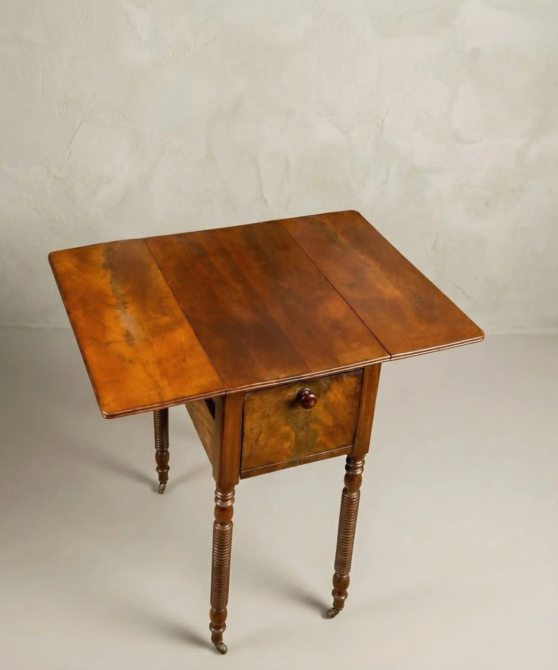 Vista desde arriba de mesa auxiliar de caoba con las dos alas abatibles desplegadas.