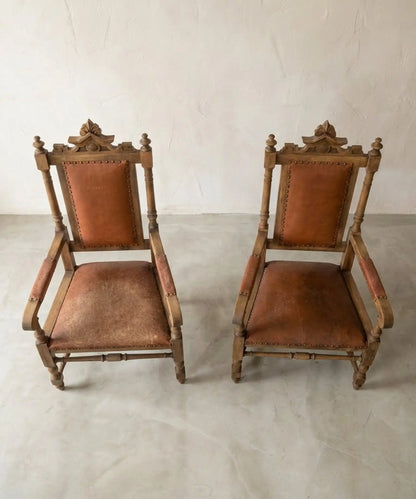 Pareja de sillones fraileros clásicos de madera y cuero marrón con tachuelas.