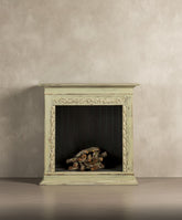  Vista frontal de la chimenea decorativa verde pátina con talla floral sobre fondo neutro.