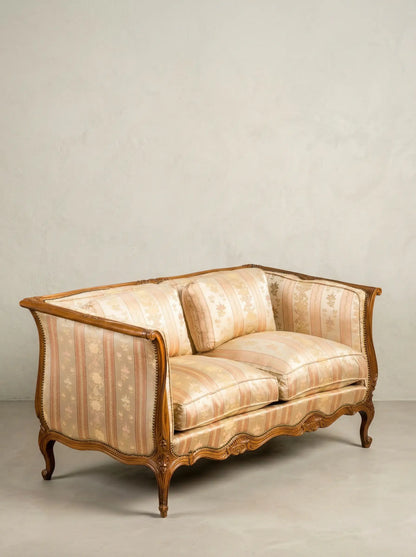 Vista diagonal de sofá clásico afrancesado mostrando patas curvas de madera y cojines mullidos.