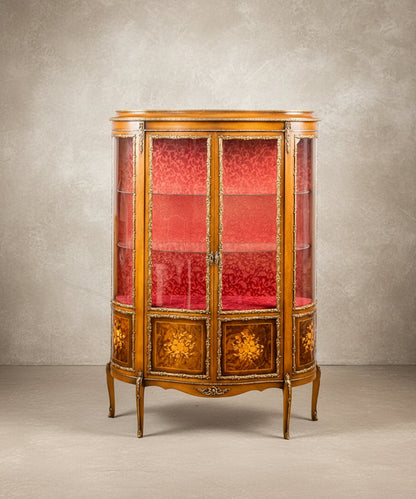 Vitrina francesa estilo Luis XV de media luna en madera dorada con fondo de damasco rojo.