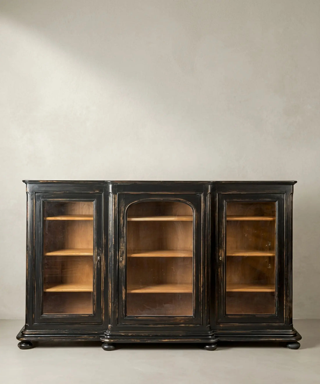 Vista frontal completa de la vitrina "Grand Palais" en madera negra envejecida con tres puertas de cristal sobre fondo neutro.