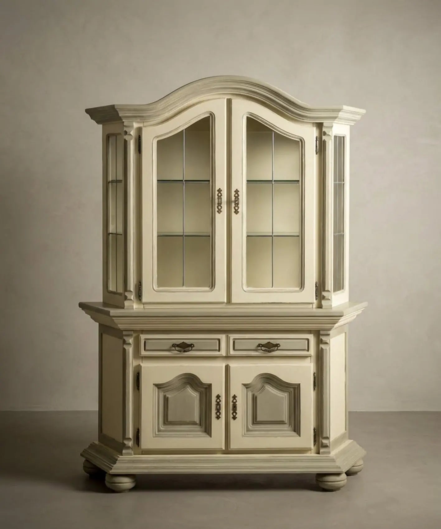 Vitrina clásica en tono crema y oliva con herrajes de bronce, diseño elegante de dos cuerpos.