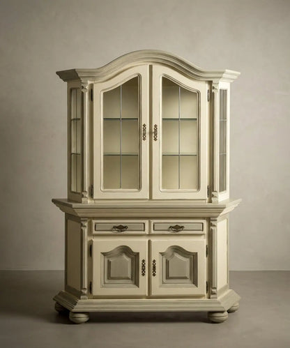 Vitrina clásica en tono crema y oliva con herrajes de bronce, diseño elegante de dos cuerpos.