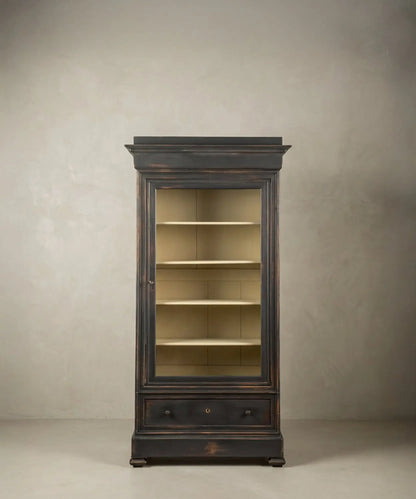Vitrina de madera negra ebonizada de estilo francés vista de tres cuartos, mostrando molduras superiores y base sólida.