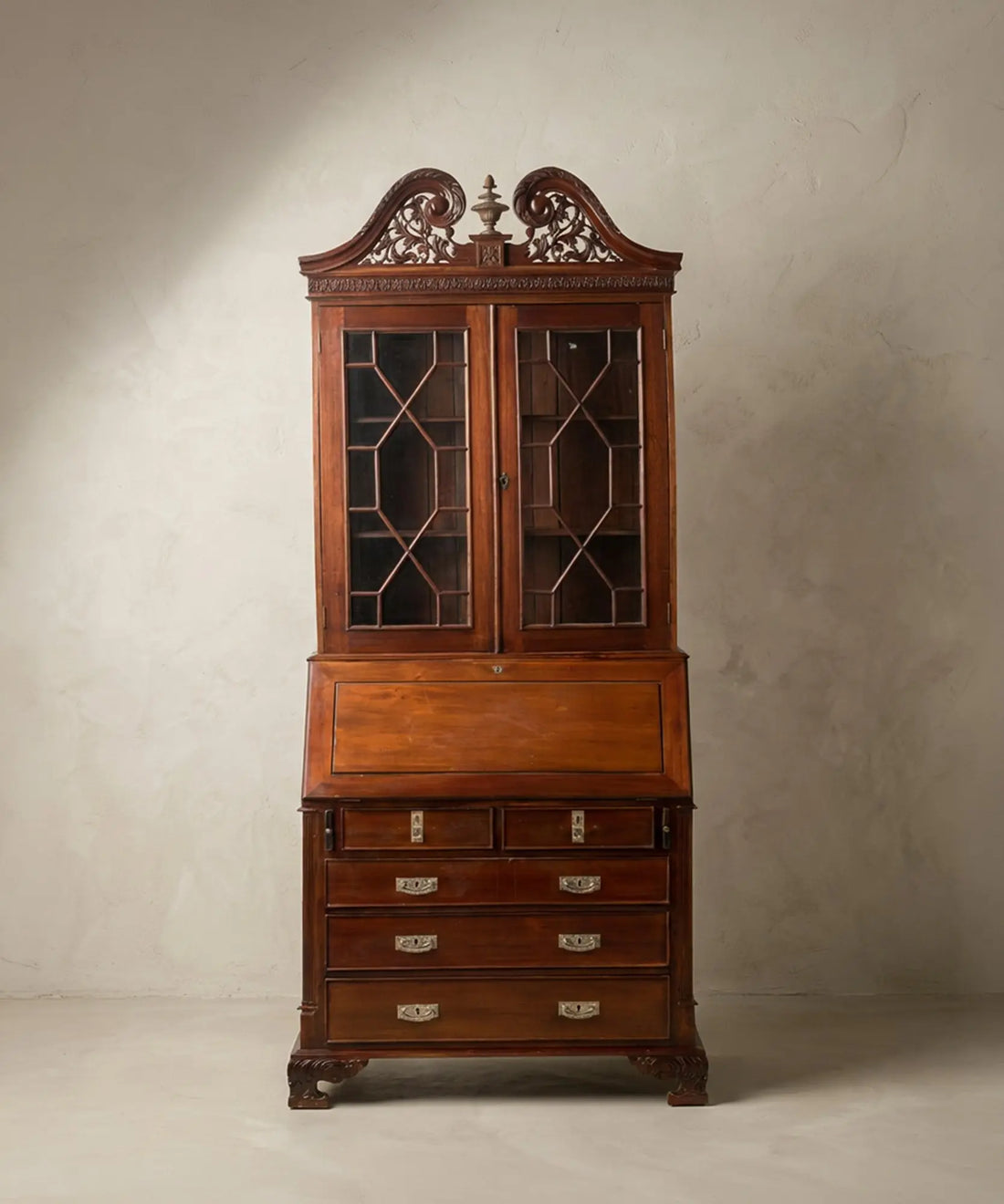  Vista frontal completa de un buró-librería de caoba estilo George III con copete tallado y puertas de cristal con tracería.