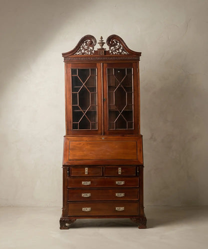  Vista frontal completa de un buró-librería de caoba estilo George III con copete tallado y puertas de cristal con tracería.